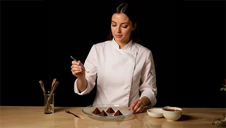 Natália em cozinha profissional emplatando doces finos